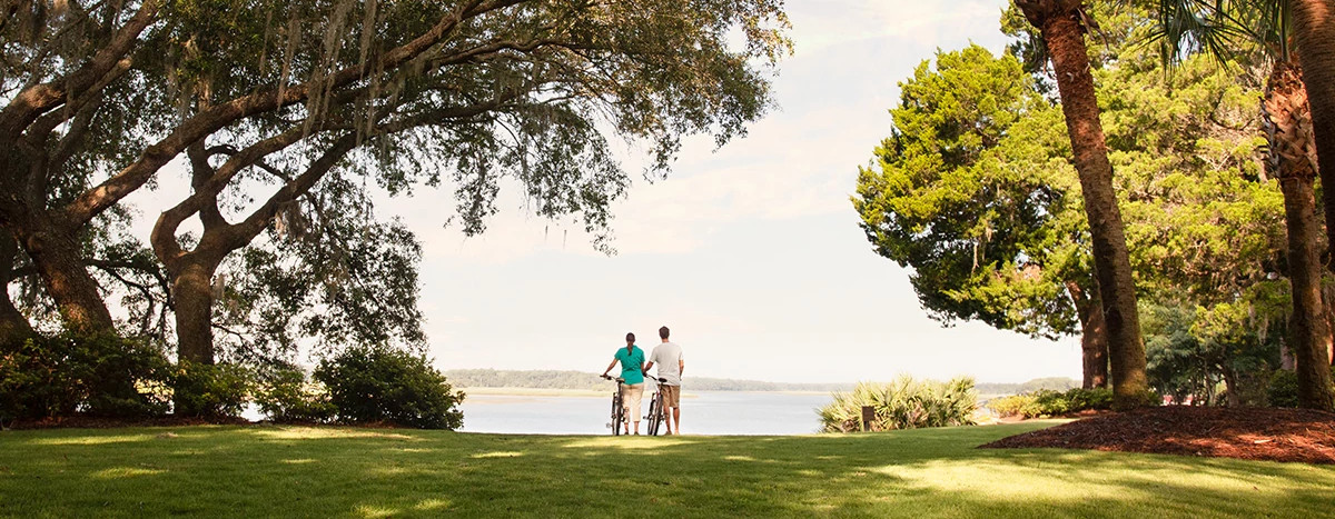 couple standing with bikes on the bank of the May River in Bluffton SC