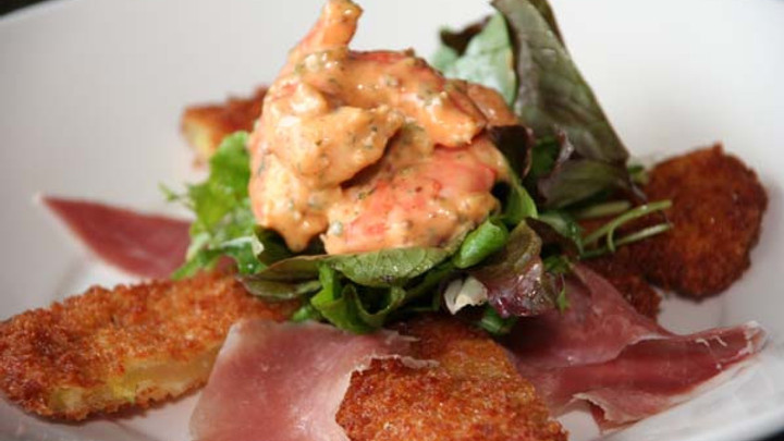 Seafood in cream sauce atop greens, ham, toast 