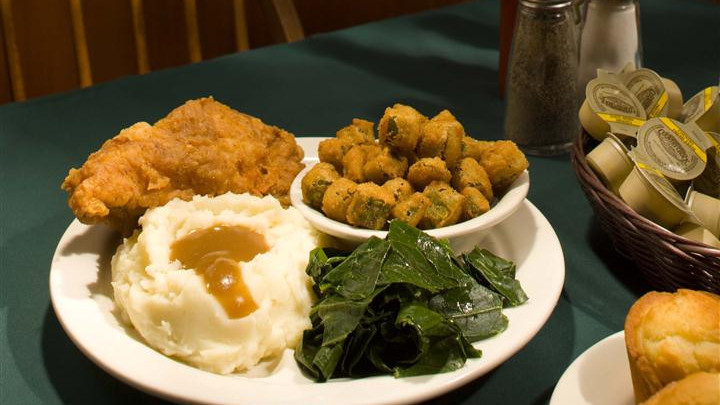 Plate of fried chicken, mashed potatoes, gravy, collards, fried okra, corn muffin, butter