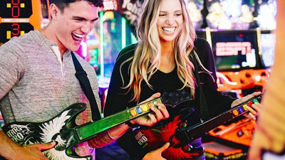 couple playing arcade guitar game at Dave & Buster's