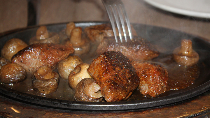 Grilled meat and mushrooms smoking on platter