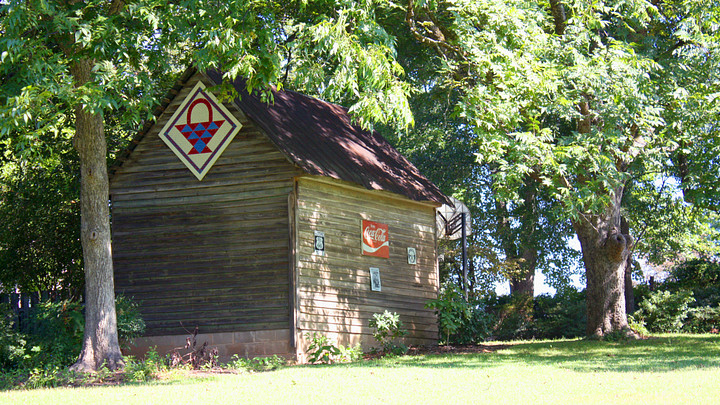 Quilt square on back of old barn surrounded by trees