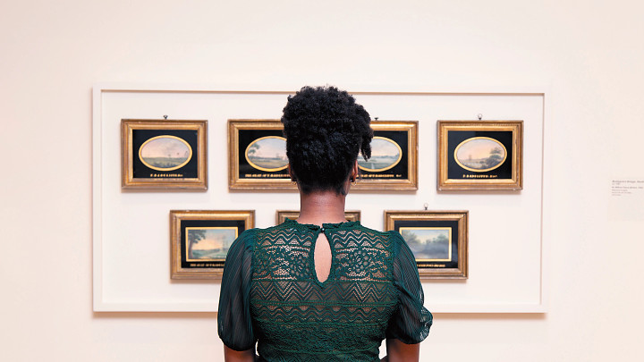 woman with her back to the camera looking at framed images